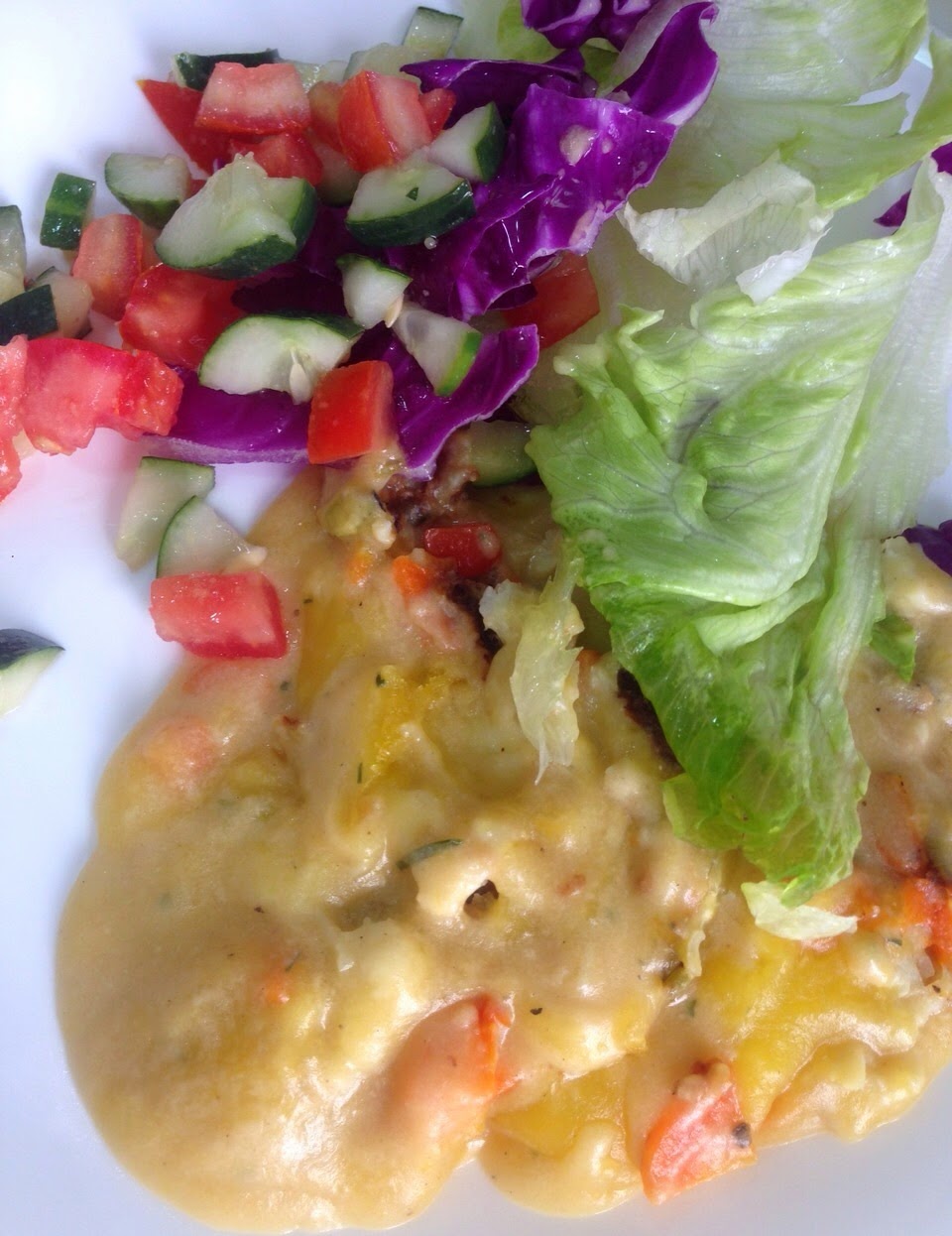 Prato com molho cremoso, salada de tomate picado e pepino, folhas de alface, em tons amarelos, vermelhos, verdes e púrpura